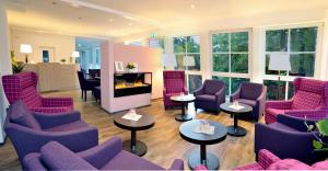 布尔格Hotel Bleske im Spreewald的客厅配有紫色椅子、桌子和窗户