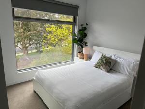 墨尔本Centrepoint Units Heidelberg的配有大窗户的客房内的白色床
