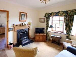 Kingholm QuayConheath Gatelodge Cottage的客厅设有壁炉和电视。