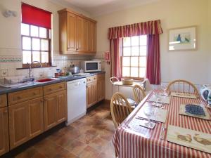 Kingholm QuayConheath Gatelodge Cottage的厨房配有木制橱柜和桌椅