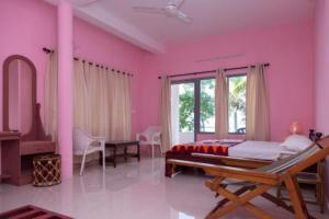 阿勒皮Orchid Lake View Homestay的卧室设有粉红色的墙壁、一张床和一张书桌