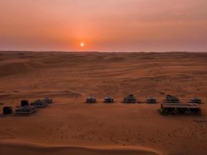 ShāhiqSands Dream Tourism Camp的日落时分沙漠中的一群骆驼