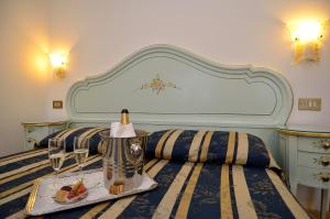 威尼斯俄里翁酒店的一张带食物托盘和一瓶葡萄酒的床