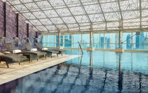多哈InterContinental Doha The City, an IHG Hotel的大楼内带椅子的游泳池