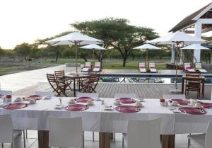 纳穆托尼艾曼雅 @埃托沙旅馆的一张桌子,上面摆放着盘子和餐巾,还有椅子和一个游泳池