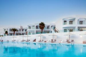 沙姆沙伊赫Meraki Resort Sharm El Sheikh Adults only的大楼前的游泳池配有椅子和遮阳伞