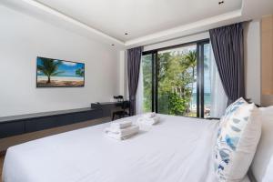 芭东海滩By The Beach Home in Patong的卧室设有一张白色大床和大窗户