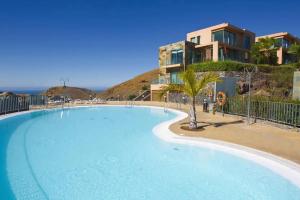 马斯帕洛马斯Holiday Home Villa Gema, spacious, scenic, Wlan ,AC的一座大型蓝色游泳池,位于大楼旁边