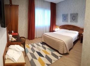 米拉波皮酒店的酒店客房设有一张大床和一张桌子。