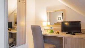 杜塞尔多夫空中瓦尔特堡酒店的客房设有书桌、电视和椅子