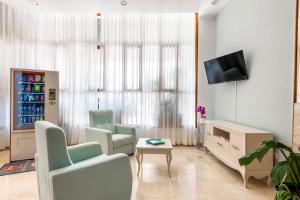 洛斯克里斯蒂亚诺斯安德里亚斯酒店的客厅配有两把椅子和电视