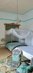 杰拉切Palazzo Caracciolo的一间卧室配有一张带天蓬的床和两把椅子