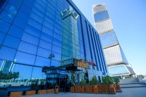 巴库Avenue Hotel Baku by Smart的一座高大的玻璃建筑,上面有标志
