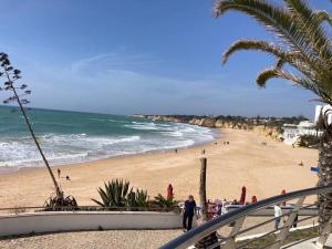 阿玛考德佩拉Luxury two BR pool view beach side apartment at Algarve's longest beach的海滩上有人在沙滩上散步