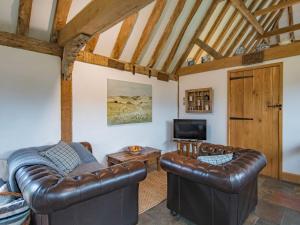 HollingbourneHeron Barn的客厅配有两张真皮沙发和一台电视机