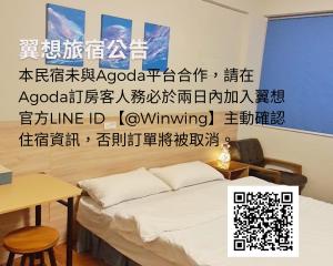 花莲市翼想旅宿-2022營運車站前花蓮民宿的一间卧室配有床,墙上有书写