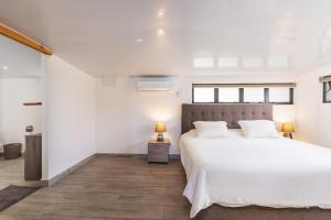 普纳奥亚Jolie Maison Vue Ocean et Moorea的白色卧室设有一张大床和一盏灯。