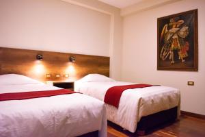 库斯科Zans Apartments Cusco的酒店客房设有两张床,墙上挂有绘画作品