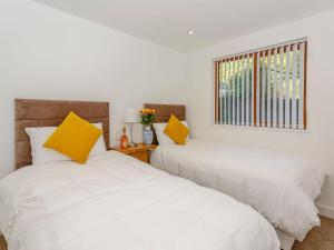 SouthowramWaterside Lodge Thirteen - Uk11853的白色客房的两张床,配有黄色枕头
