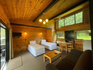 罗托鲁瓦Lakes Lodge Okataina的客房设有两张床、一张沙发和一张桌子。