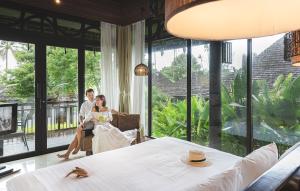 拉威海滩The Vijitt Resort Phuket - SHA Extra Plus的坐在带大窗户的房间的新娘和新郎
