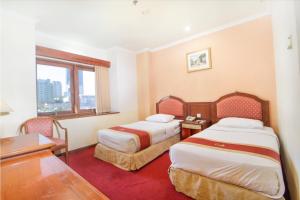 泗水Hotel Bisanta Bidakara Tunjungan的酒店客房设有两张床、一张书桌和一个窗户。