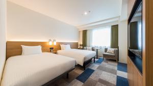 横滨JR-East Hotel Mets Yokohama Sakuragicho的一间酒店客房,设有两张床和电视