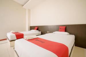 纳闽巴霍RedDoorz near Pantai Pede的红色和白色的客房内的两张床