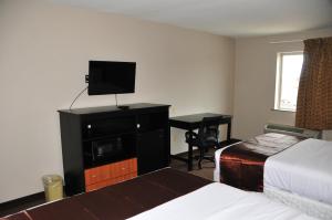 巴吞鲁日Paradise Inn & Suites的酒店客房配有一张床、一台电视和一张书桌。