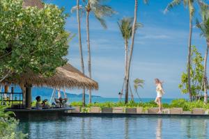 波普托Holiday Inn Resort Samui Bophut Beach, an IHG Hotel的站在度假胜地游泳池边缘的女人