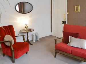 莫珀斯Drovers的客厅配有2把红色椅子和桌子
