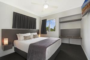 Cooroy库罗伊豪华汽车旅馆公寓的一间卧室设有一张大床和一个窗户。