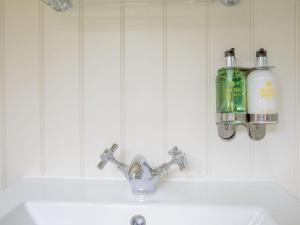 Burton OveryUnder Willows - Uk12608的浴室水槽配有水龙头和墙上的2瓶水。
