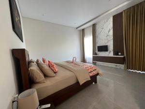 纳闽巴霍Villa Niang Ando的一间卧室配有带枕头的床铺和电视。