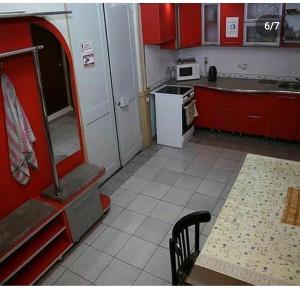 巴甫洛达尔мини-отель "Алатау"的厨房配有红色橱柜、桌子和冰箱