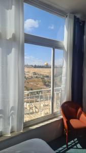 耶路撒冷耶路撒冷全景酒店 的一间卧室设有窗户和椅子,享有美景