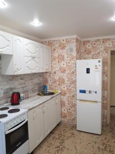 巴甫洛达尔квартира的厨房配有白色橱柜和白色冰箱。
