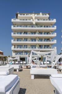 丽都迪萨维奥维士塔梅赫套房酒店的海滩上的酒店,配有白色的床和遮阳伞