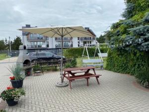 凯蒂赖贝西Apartamenty na Zaciszu的野餐桌和雨伞位于房子前