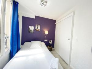 巴黎阿维亚迪克酒店的一间小卧室,配有一张白色的床和紫色的墙壁