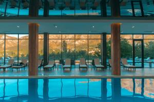 ChimganARCHAZOR Mountain Resort的客房设有游泳池、椅子和窗户。