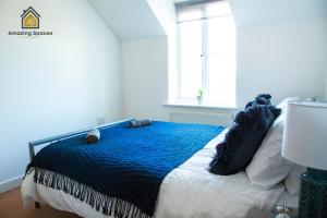 沃灵顿Cosy 2 Bed Flat Sleeps 4 with Free Parking by Amazing Spaces Relocations Ltd的一间卧室配有一张带蓝色毯子的床和窗户。