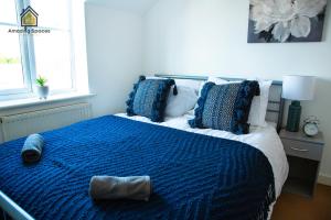 沃灵顿Cosy 2 Bed Flat Sleeps 4 with Free Parking by Amazing Spaces Relocations Ltd的一间卧室配有一张带蓝色棉被和枕头的床