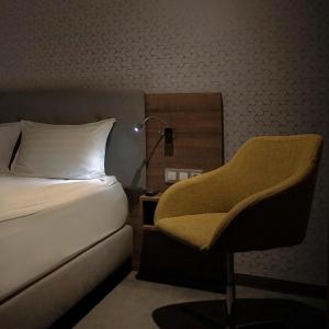 罗兹Abton Hotel的一间卧室配有一张床、一把椅子和一盏灯