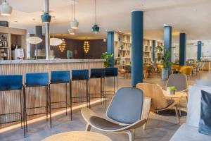 奥伯豪森Hotel Oberhausen Neue Mitte affiliated by Meliá的一间设有蓝色椅子的餐厅和一间酒吧