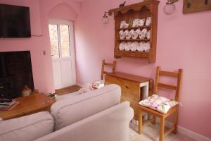莱明斯特The Gardener's Cottage的客厅设有粉红色的墙壁和白色的沙发