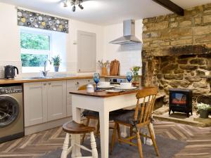 SilsdenBeckside Cottage的厨房配有桌椅和壁炉。