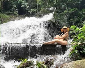 AnnitapolisCabanas Pousada Esmeraldas的坐在瀑布上的戴帽子的女人