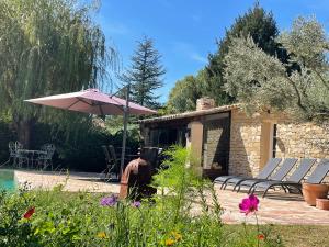 弗维沃FUVOLEA, Maison de vacances à 15 min du centre d'Aix-en-Provence, piscine chauffée en saison - jardin - parking privé gratuit的庭院配有遮阳伞和桌椅。