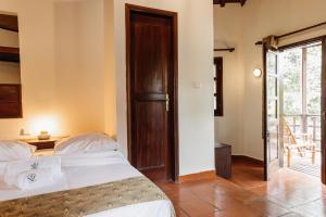 圣多美Roça Vale dos Prazeres的一间卧室设有一张床和一个滑动玻璃门